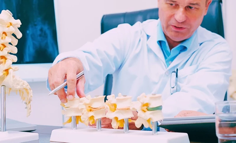 Doctor explaining various spine diseases by the example of plastic models.