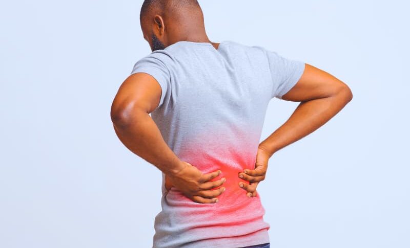 Herniated Discs After Car Accidents: Chiropractic vs. Surgical Pathways 1 Guy holding both hands on lower back, pain in spine, inflamed zone highlighted in red.