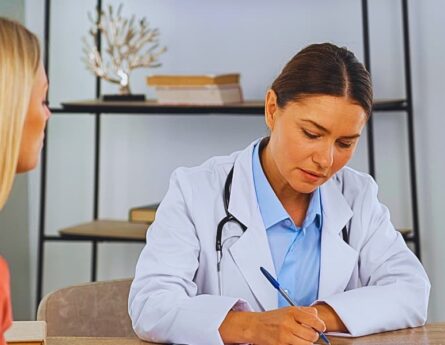 Female doctor writing a prescription for her female patient.