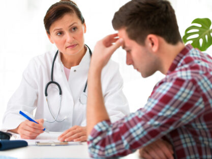 man with headache talking to doctor