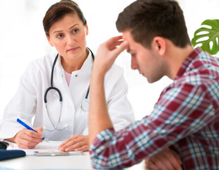 man with headache talking to doctor
