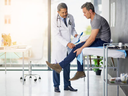 Doctor checking man's knee.