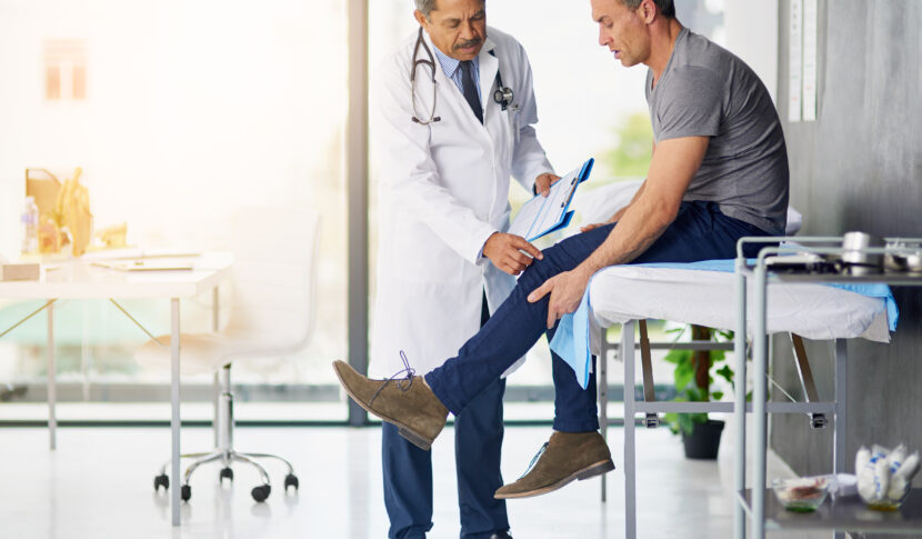 Doctor checking man's knee.