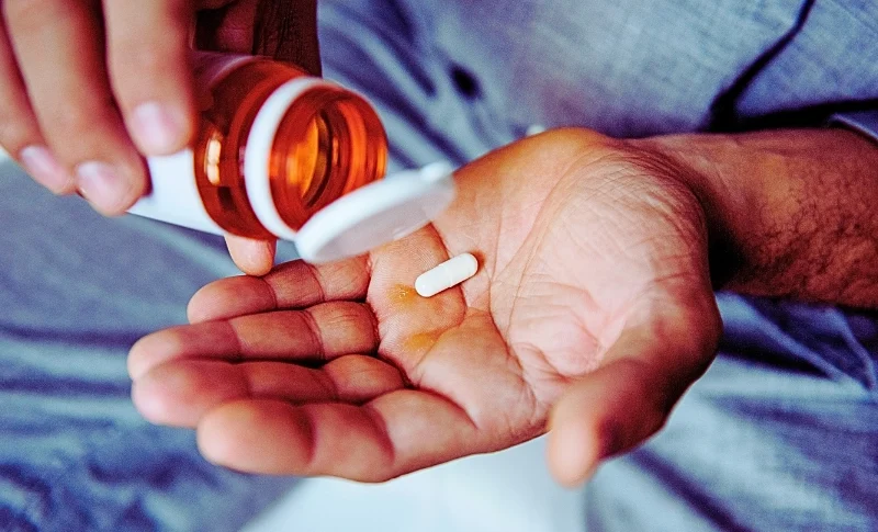 Can Chiropractic Care Reduce Reliance on Pain Medication After an Injury? 1 a person pouring a single white capsule pill from an amber prescription bottle into their open palm.